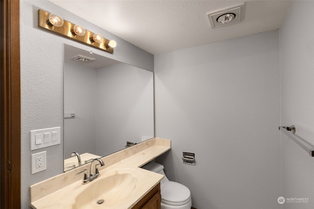 bathroom with vanity, a textured ceiling, and toilet