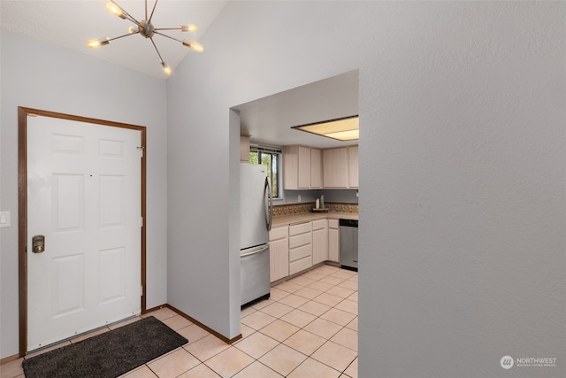 kitchen with lofted ceiling, appliances with stainless steel finishes, a notable chandelier, and light tile patterned floors