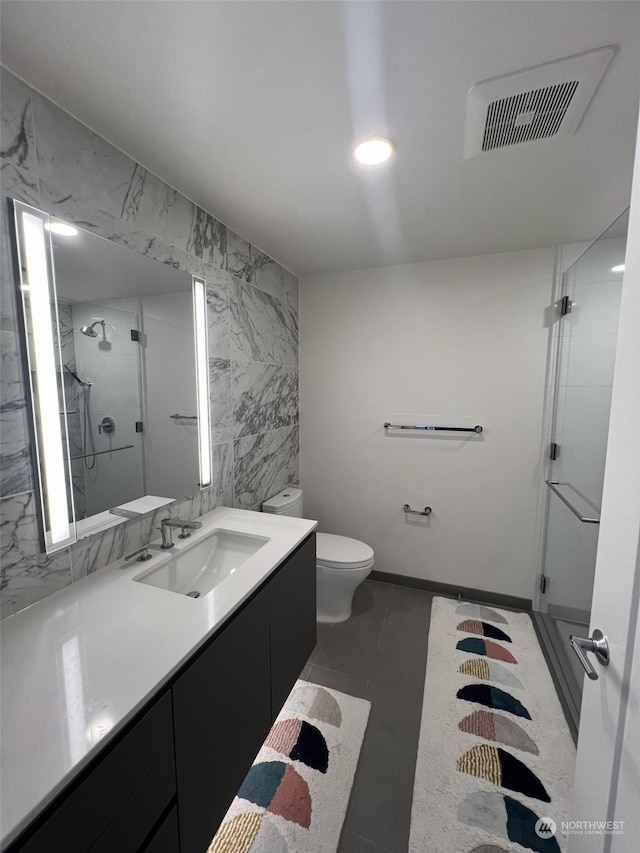 bathroom featuring tile walls, tile patterned flooring, an enclosed shower, vanity, and toilet