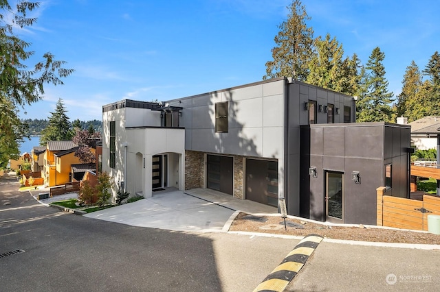 view of front of home with concrete driveway, stucco siding, stone siding, and an attached garage