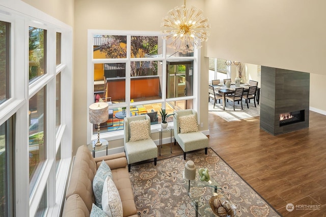 interior space with a multi sided fireplace, wood finished floors, a notable chandelier, and plenty of natural light
