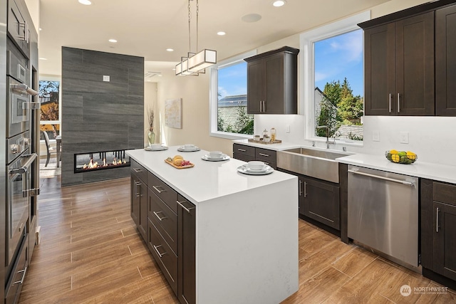 kitchen featuring a center island, a sink, light countertops, appliances with stainless steel finishes, and wood tiled floor