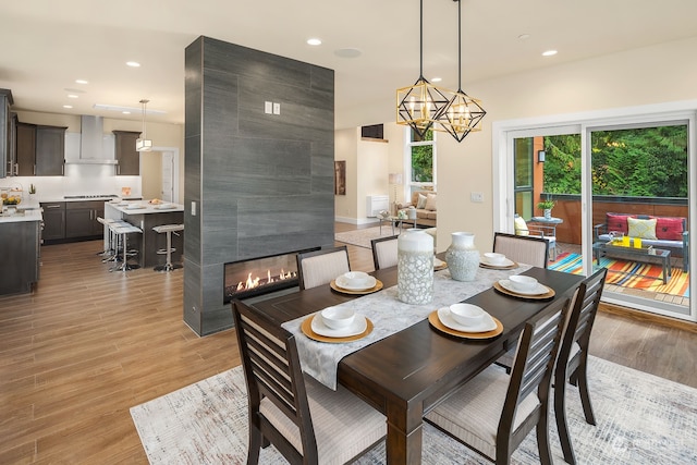 dining room featuring a fireplace, an inviting chandelier, and light hardwood / wood-style flooring