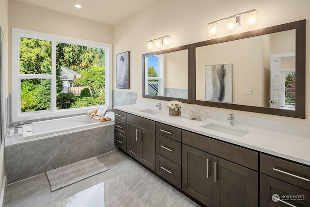 full bath featuring a sink, double vanity, recessed lighting, and a garden tub