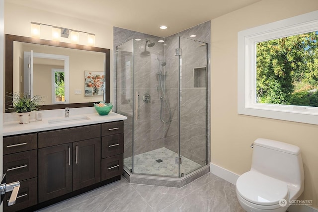 full bathroom with toilet, a stall shower, baseboards, and vanity