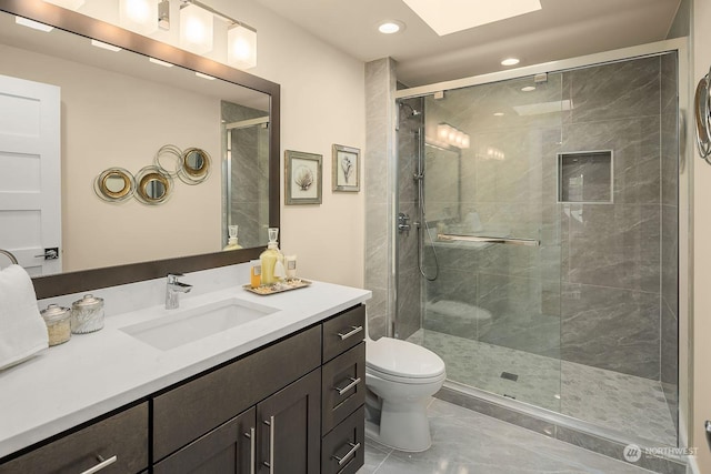 full bathroom with toilet, vanity, a skylight, marble finish floor, and a stall shower