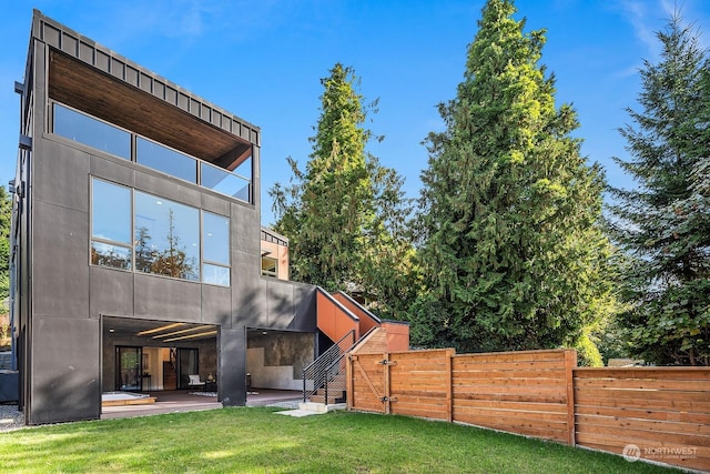 rear view of property featuring a yard, stairway, fence, and a patio