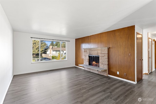 unfurnished living room featuring a fireplace, wood walls, and dark hardwood / wood-style flooring