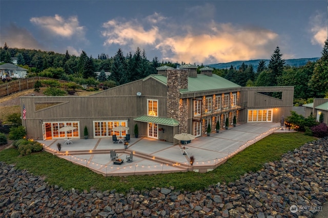 back house at dusk featuring french doors and a patio area