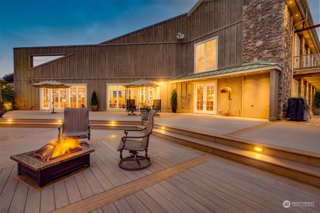 deck at dusk featuring french doors and an outdoor fire pit