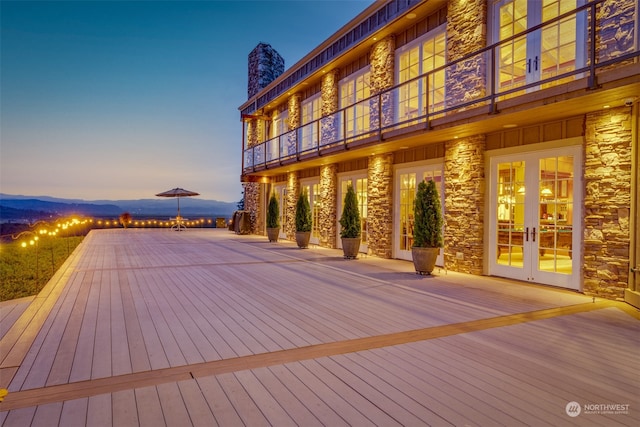 deck at dusk featuring a mountain view and french doors