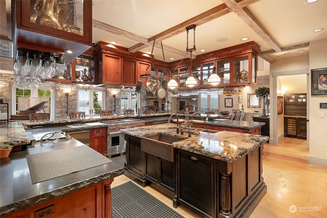 kitchen featuring a center island with sink, beam ceiling, sink, and decorative light fixtures