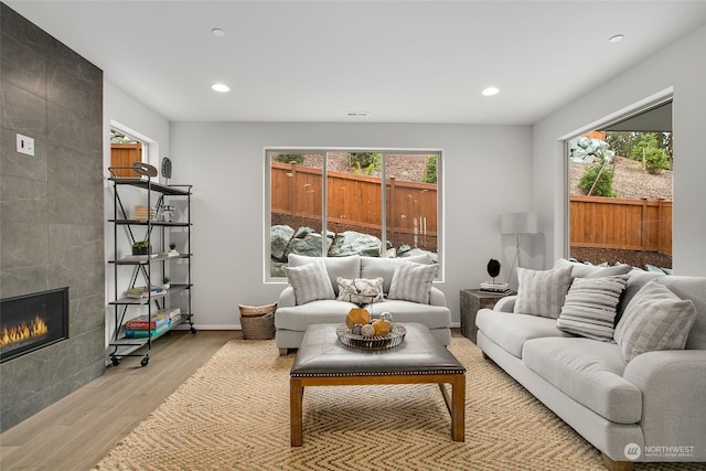 living room featuring a tile fireplace and light hardwood / wood-style floors