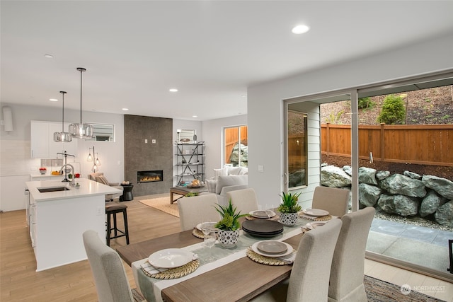 dining area with sink, a tile fireplace, plenty of natural light, and light hardwood / wood-style flooring