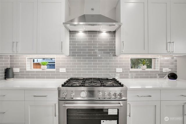 kitchen featuring white cabinetry, wall chimney exhaust hood, decorative backsplash, and stainless steel gas stove