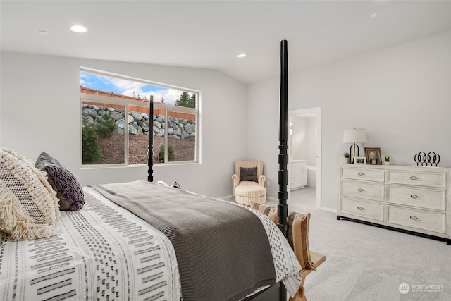 carpeted bedroom with ensuite bath and vaulted ceiling