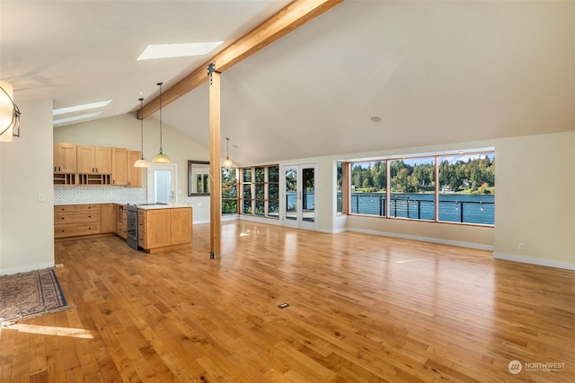 unfurnished living room featuring a skylight, beam ceiling, and light hardwood / wood-style floors