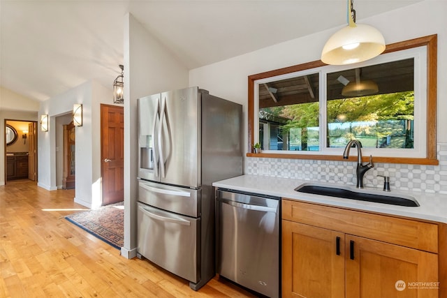 kitchen with stainless steel appliances, backsplash, light hardwood / wood-style floors, and lofted ceiling