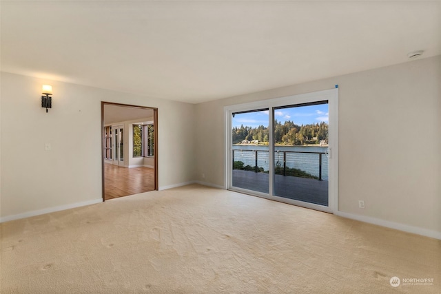 unfurnished room with light colored carpet and a water view