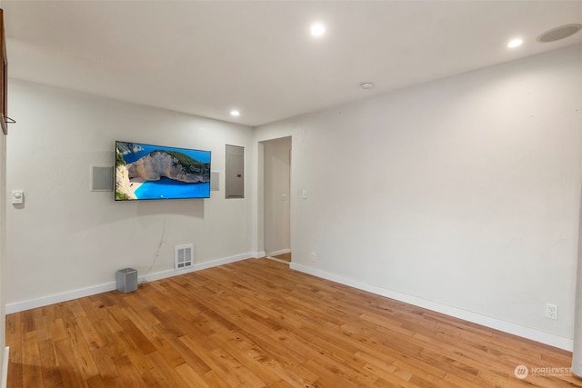 empty room featuring electric panel and hardwood / wood-style flooring