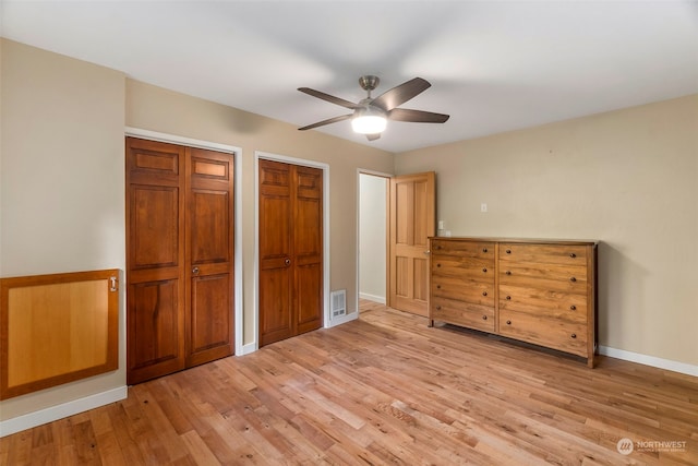 unfurnished bedroom with ceiling fan, multiple closets, and light hardwood / wood-style floors