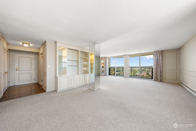 unfurnished living room with ornamental molding, baseboard heating, and carpet flooring