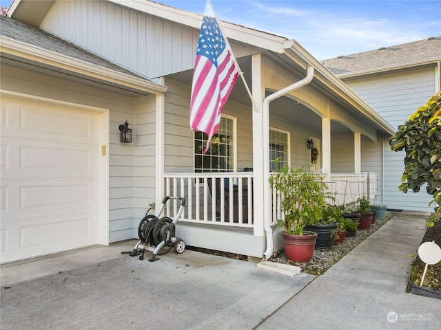 view of exterior entry featuring a garage and covered porch