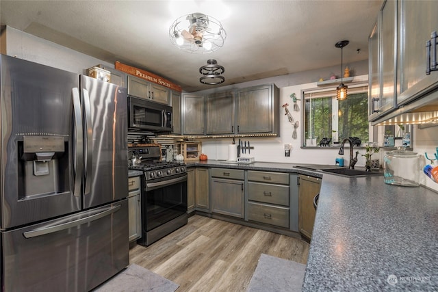 kitchen featuring hanging light fixtures, light hardwood / wood-style floors, stainless steel appliances, a textured ceiling, and sink