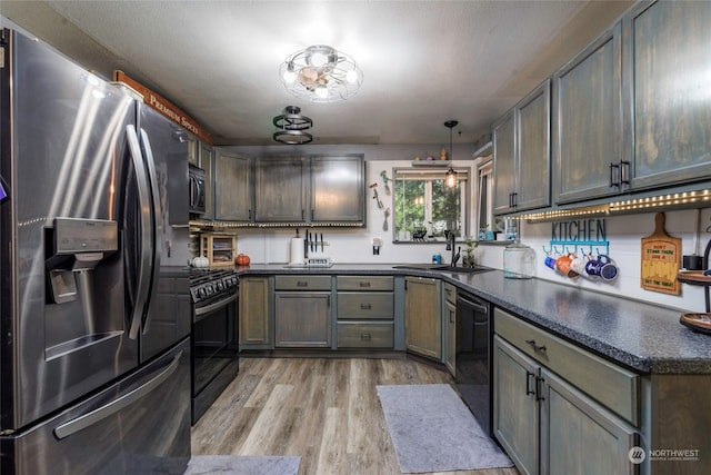 kitchen featuring black appliances, sink, light hardwood / wood-style flooring, and decorative light fixtures