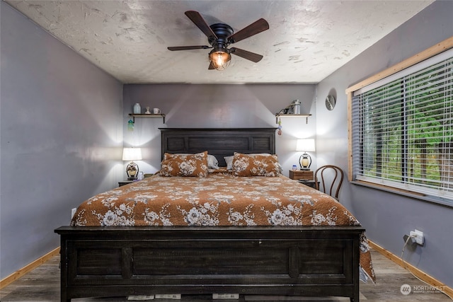 bedroom with ceiling fan, dark hardwood / wood-style floors, and a textured ceiling