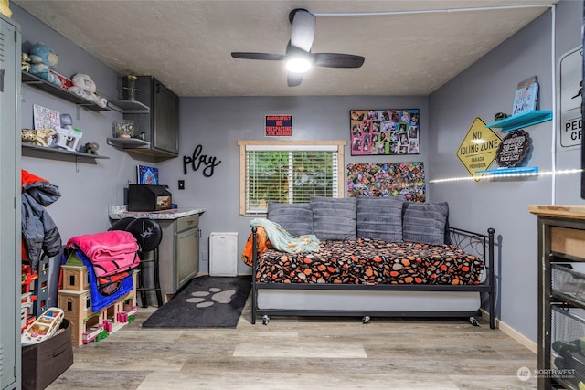 bedroom with a textured ceiling, light hardwood / wood-style floors, and ceiling fan