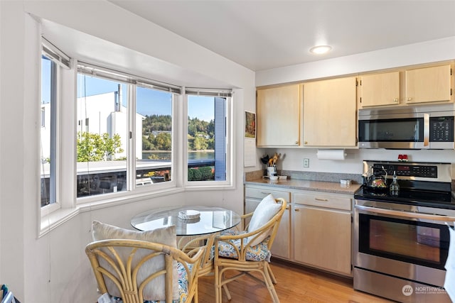 kitchen with light brown cabinets, appliances with stainless steel finishes, and light hardwood / wood-style floors