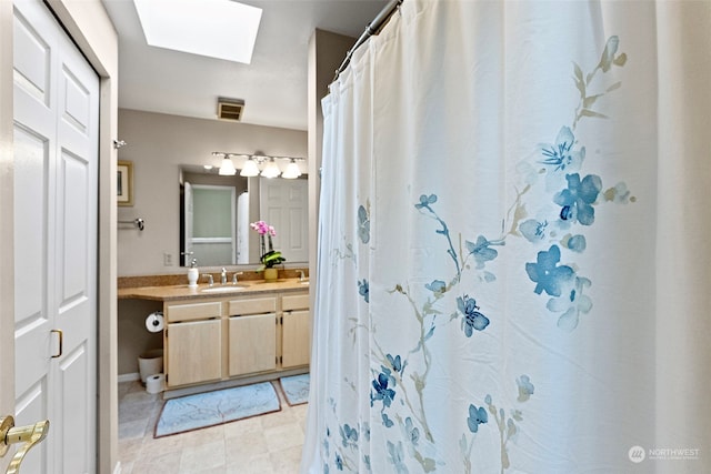 bathroom featuring a skylight, vanity, and a shower with curtain