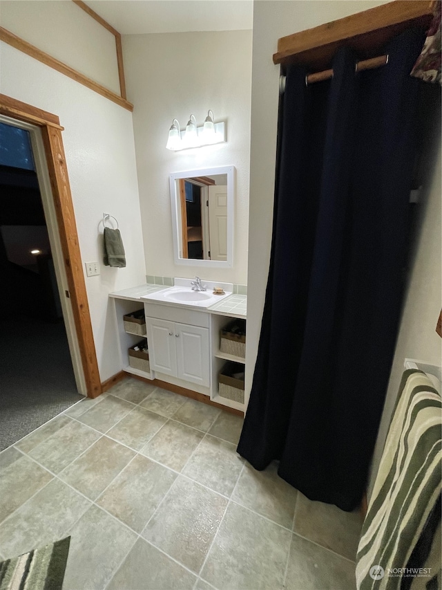 bathroom featuring vanity, tile patterned flooring, and vaulted ceiling