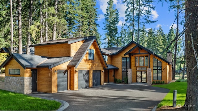 modern home with driveway and stone siding