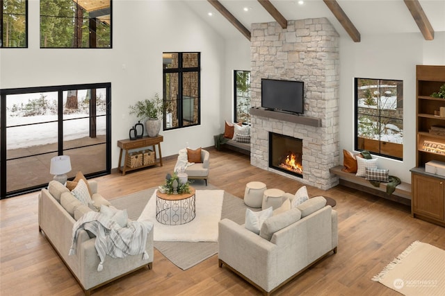 living room with a fireplace, light wood-type flooring, and beamed ceiling