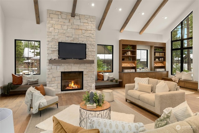 living room featuring a fireplace, light hardwood / wood-style flooring, high vaulted ceiling, and plenty of natural light