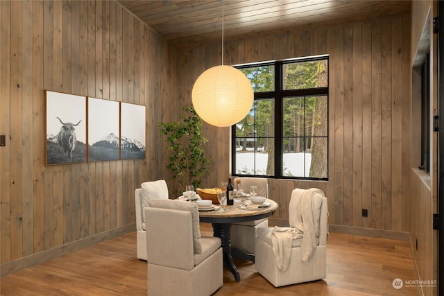 dining room with wooden walls, light hardwood / wood-style flooring, and wood ceiling