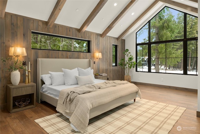 bedroom featuring beamed ceiling, hardwood / wood-style floors, multiple windows, and wooden walls