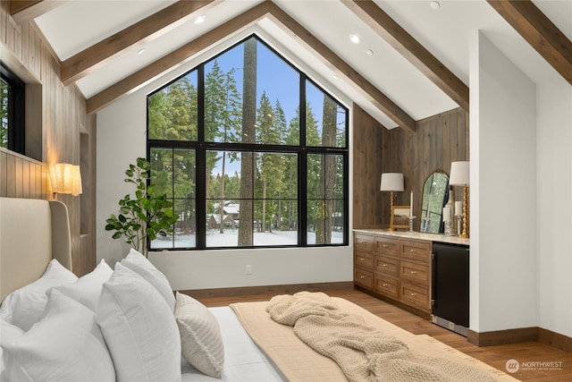 bedroom with beamed ceiling, high vaulted ceiling, wood walls, refrigerator, and wood-type flooring