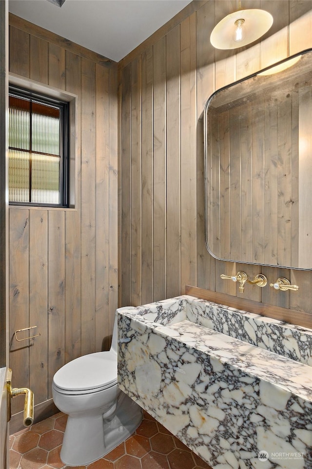 bathroom featuring tile patterned flooring, toilet, and wood walls