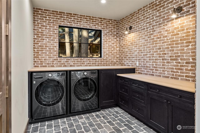 laundry area with separate washer and dryer, cabinets, and brick wall