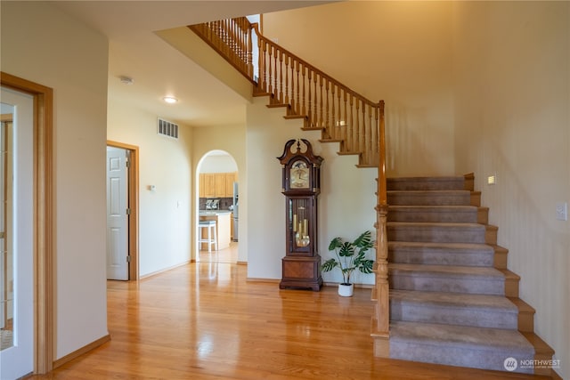 stairs with a towering ceiling and hardwood / wood-style flooring