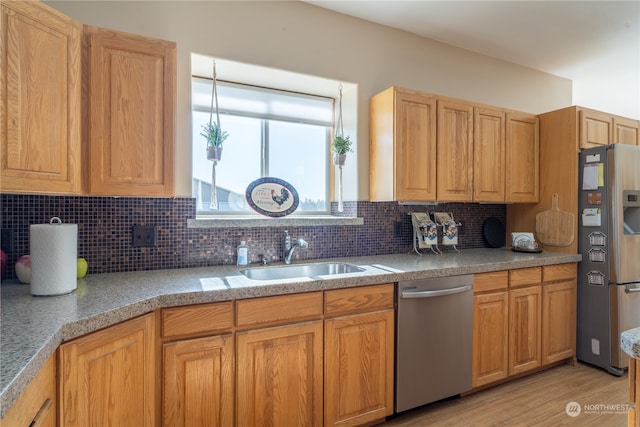 kitchen featuring appliances with stainless steel finishes, sink, tasteful backsplash, and light hardwood / wood-style flooring