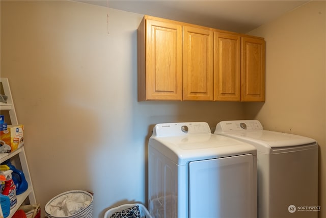 washroom with washer and dryer and cabinets