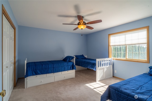 bedroom with ceiling fan, light colored carpet, and a closet