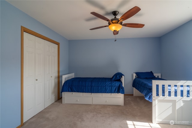 carpeted bedroom featuring ceiling fan and a closet