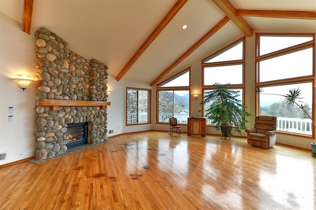 unfurnished living room with high vaulted ceiling, beamed ceiling, light hardwood / wood-style flooring, and a fireplace