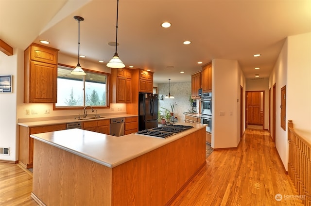 kitchen with pendant lighting, light wood-type flooring, sink, a kitchen island, and appliances with stainless steel finishes