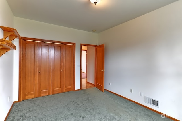 unfurnished bedroom with light colored carpet and a closet